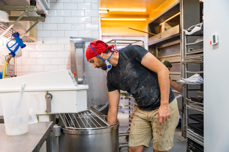 Male baker of bakery in the workshop of artisan bakery preparing the sourdoughs in the machines
