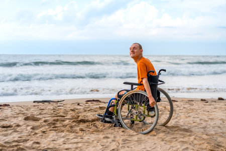 Portrait of a disabled person in a wheelchair on the beach laughing by the seaの写真素材