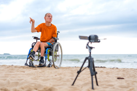 Portrait of a disabled person in a wheelchair on the beach recording a video clipの写真素材