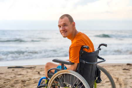 Portrait of a disabled person in a wheelchair on the beach enjoying the freedom of the sea and natureの写真素材