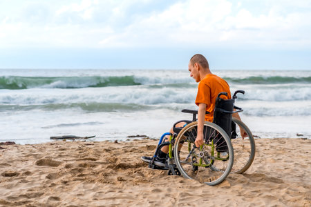 Portrait of a disabled person in a wheelchair on the beach pensive by the seaの写真素材