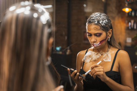 Preparations for the Halloween party, detail of a client finished makeup looking in the mirror and...