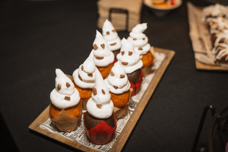 Halloween food and sweets in the shape of pumpkins at a party, chocolate ghost cupcakesの写真素材