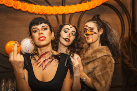 Female friends in costumes at halloween party with friends in disco nightclub, looking at cameraの写真素材