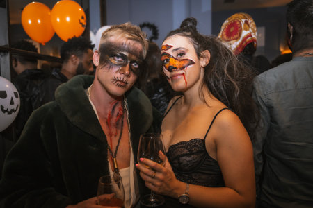 Portrait of a couple in costumes and makeup at the halloween party with friends in a disco nightclubの写真素材