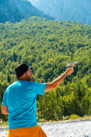 Drone pilot landing the drone in hand on the mountain in the Valbona natural park in summer....