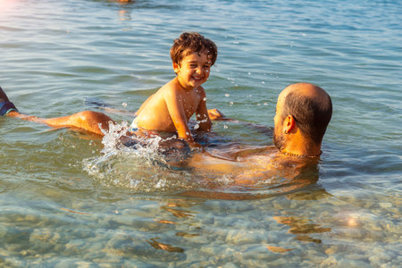 Father and son enjoying summer vacation bathing on the beachの写真素材