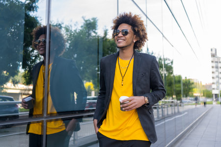 Casual and stylish african american man drinking take away coffee walking along the cityの写真素材