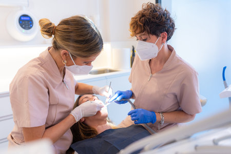 Dentist and assistant examining the mouth of a patient lying on the chair of a clinicの写真素材
