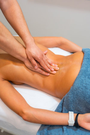Physiotherapeutic massage to an unrecognizable woman lying on a stretcher on her backの写真素材