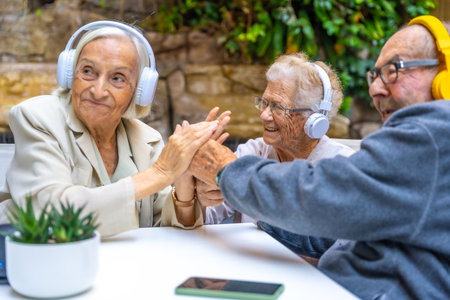 Seniors enjoying music using headphones sitting on a garden in a nursing homeの写真素材