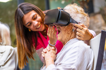 Nurse next to an amazed old woman using virtual reality goggles in a geriatricの写真素材