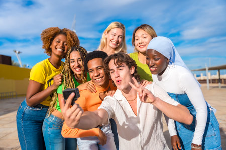 Multi-ethnic and gender friends gesturing success while taking a selfieの写真素材
