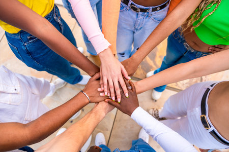 Top view close-up photo of multi-ethnic young people joining hands in a huddleの写真素材