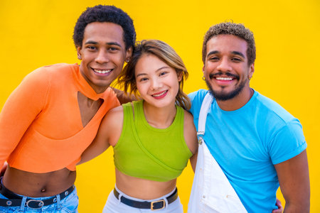 Gender and ethnic diverse people posing smiling at camera in a yellow background