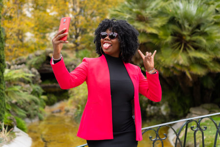 Stylish african businesswoman taking a funny selfie outdoorsの写真素材