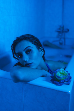 Vertical artistic portrait with blue lights of a sensual woman in a relaxing moments in a hot tubeの写真素材