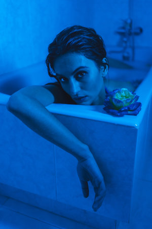 Vertical artistic portrait with blue lights of a sensual relaxed woman in a relaxing moments in a hot tubeの写真素材