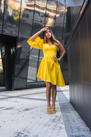 Vertical portrait of a beauty female model with yellow dress posing in a modern cityの写真素材