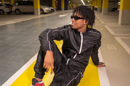 Portrait of an African music artist looking away sitting on an urban garageの写真素材