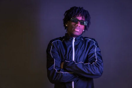 Dark studio portrait of a proud african young artist standing with arms crossedの写真素材