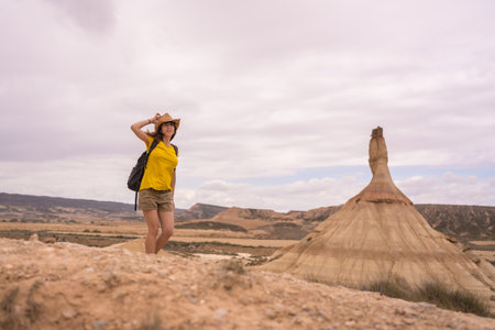 Woman holding her hat to blow with the wind in a desertの写真素材