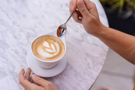 Top view of a woman about to drink a perfect coffee cup in an outdoor terraceの写真素材