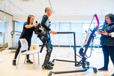 Mechanical exoskeleton. Physiotherapy medical assistant lifting disabled person with robotic...