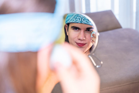 View from the mirror of a transgender person making up at home in the living roomの写真素材
