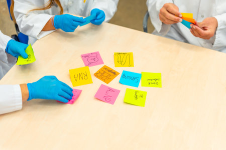 Close-up photo of group of scientists during a brainstorm study using notes in labの写真素材