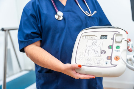 Close-up photo of a cardiologist holding a defibrillator and explaining how to use itの写真素材
