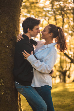 Romantic scene of a couple about to kiss leaning on a treeの写真素材