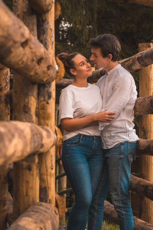 Vertical photo of a couple standing embraced together between wood rails in the countrysideの写真素材