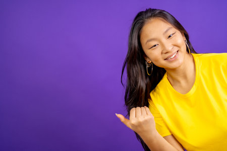 Studio photo with purple background of a chinese woman inviting to come with handの写真素材