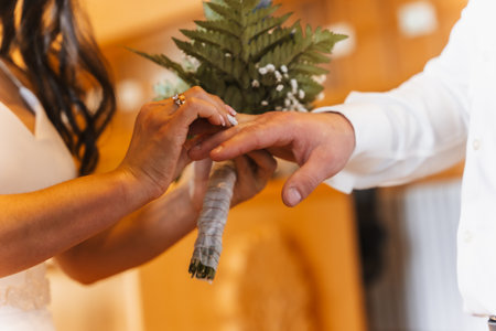 Woman putting the ring on the groom at a wedding, marriage ceremonyの写真素材