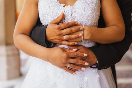 Black ethnic groom holding hands at a beautiful wedding and showing the rings, marriage portraitsの写真素材