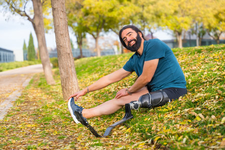 Happy man with an artificial leg stretching after exercising in an urban park