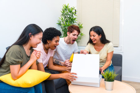 Happy multiracial friends sitting on a couch opening pizza box to eat at homeの写真素材