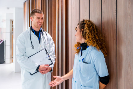 Team work of a female nurse and doctor talking in the corridor of a hospitalの写真素材