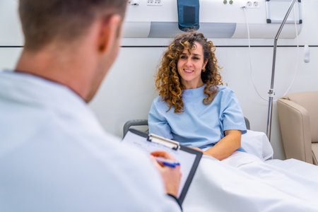 Rear view of an unrecognizable doctor attending female patient on hospital bedの写真素材