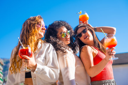 Playful women drinking cocktails and dancing on a rooftop enjoying summer and partyingの写真素材