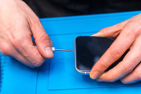 Close-up of the hands of a male expertise repairing a mobile phone in a technology workshop