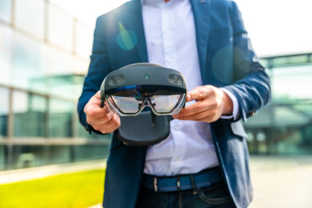 Cropped photo with close-up of the hands of a businessman holding an innovative augmented vision glasses outdoorsの写真素材