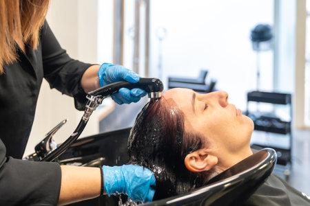 Relaxed woman with eyes closed washing her hair in a beauty hair salonの写真素材
