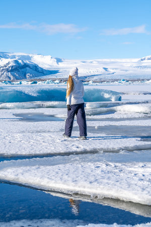 Woman walking on the ice of the frozen Jokulsarlon lake on vacation in Icelandの写真素材