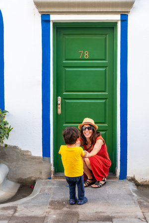 A woman and a child are standing in front of a green door with the number 78 on itの写真素材