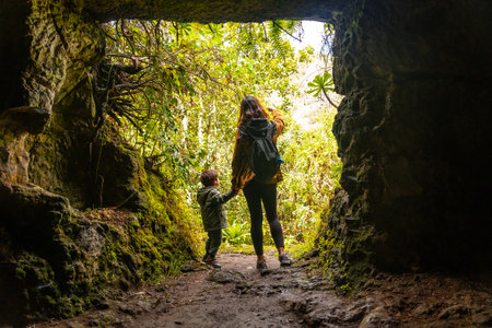A woman and a child are standing in a cave. The woman is holding the child's handの写真素材