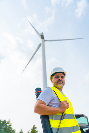 Vertical photo of a mature caucasian male engineer looking at camera standing with drawing tube next...