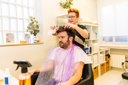 Hairdresser adjusting the capillary prosthesis to a man sitting in the salon