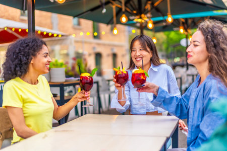Friends drinking cocktails in an outdoor terrace of a bar in the city